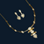 Gold necklace and earrings on a red background with decorative leaves.