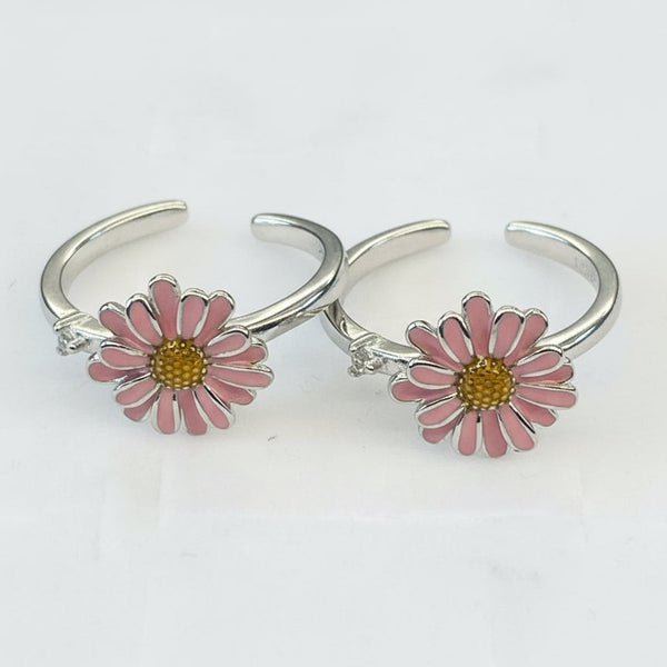 Silver open rings with pink daisy flowers on a white background