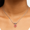 Necklace with a heart-shaped pendant on a person's neck against a neutral background