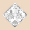 Diamond-shaped silver foil with two seated figures and a lotus design on a white background