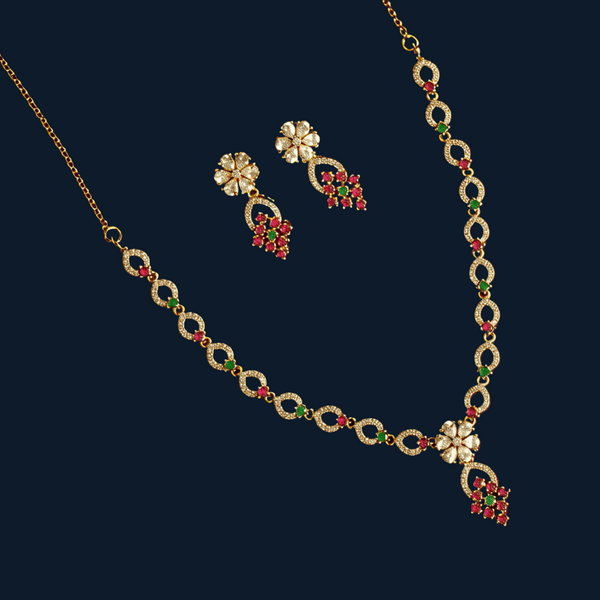 Gold necklace and earrings with floral designs on a red background