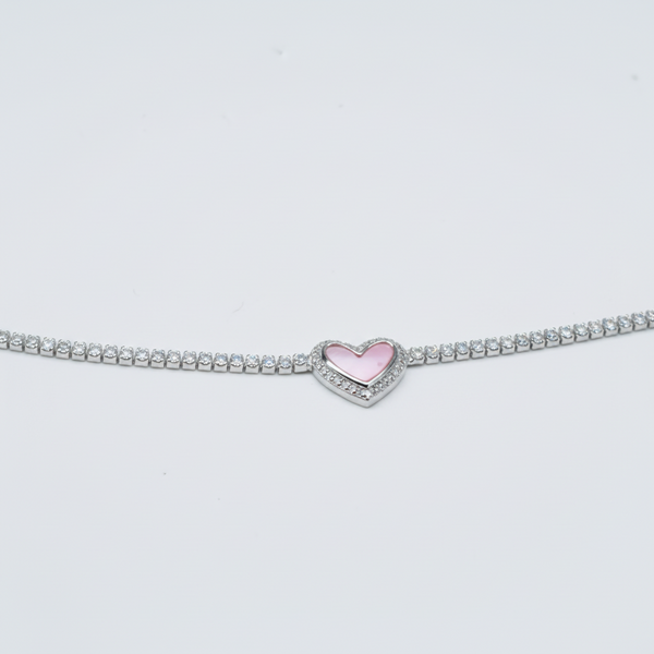 Silver bracelet with a pink heart charm on a gray background