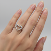 Silver heart-shaped ring on a light gray background
