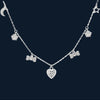 Silver necklace with heart and bow-shaped charms on a dark background