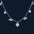 Silver necklace with heart and bow-shaped charms on a dark background