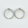 Two silver hoop earrings on a light gray surface