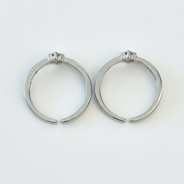Two silver hoop earrings on a light gray surface