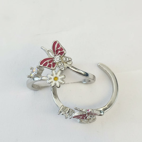 Silver ring with butterfly and flower design on a light gray background
