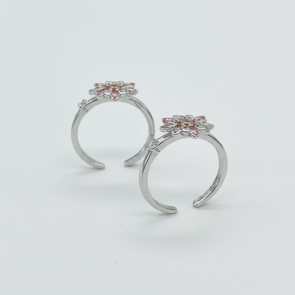 Pair of silver hoop earrings with decorative tops on a light gray background