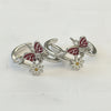 Silver ear cuff with red butterfly and white flower designs on a light gray background