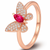 Rose gold butterfly ring with red gemstone and diamonds on a white background