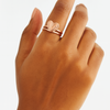 Rose gold heart-shaped ring on a person's finger against a white background