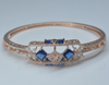 Rose gold bracelet with blue gemstones on a light gray background