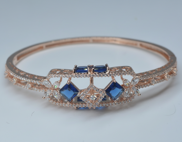 Rose gold bracelet with blue gemstones on a light gray background
