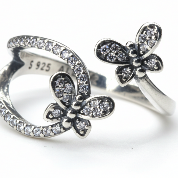Butterfly-shaped silver ring with embedded stones on a white background