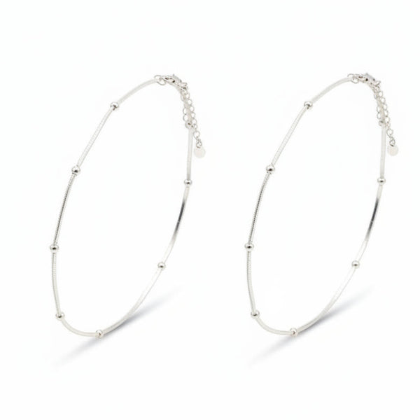 Two silver anklets on a white background
