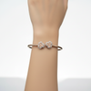 Rose gold bracelet with floral designs on a light gray background