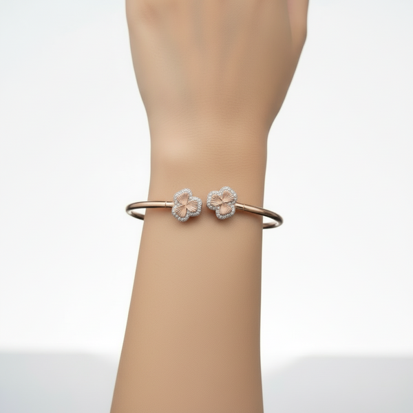 Rose gold bracelet with floral designs on a light gray background