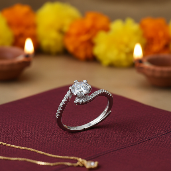 Silver ring with a diamond on a maroon fabric background with Diwali decorations.